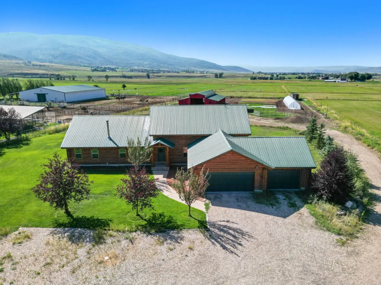 A home in the middle of a field with mountains in the background.