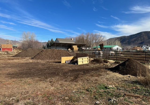 A pile of dirt in a field with mountains in the background.