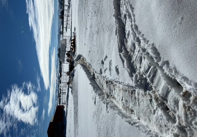 A view of a snow covered field with a blue sky.